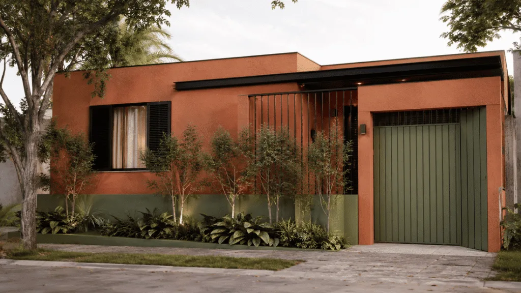Fachada de casa térrea moderna em tom terracota fosco, com detalhes em verde-musgo no portão e esquadrias em preto fosco, cercada por vegetação.